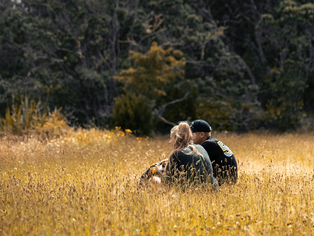 a couple of people that are sitting in the grass